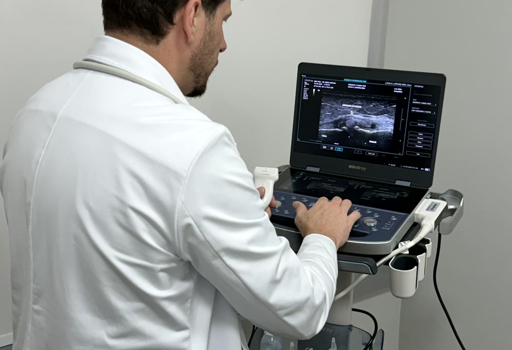 Dr. Rúbio Arruda avaliando o joelho por ultrassom no consultório